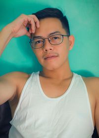 Portrait of handsome man wearing eyeglasses and tank top against wall at home