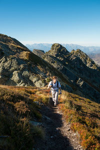 High angle view of young man hiking on mountain against clear sky