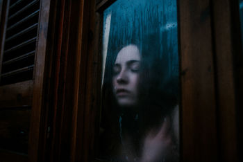 PORTRAIT OF WOMAN LOOKING THROUGH WINDOW