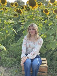 Portrait of young lady in field of sunflowers finding beauty 