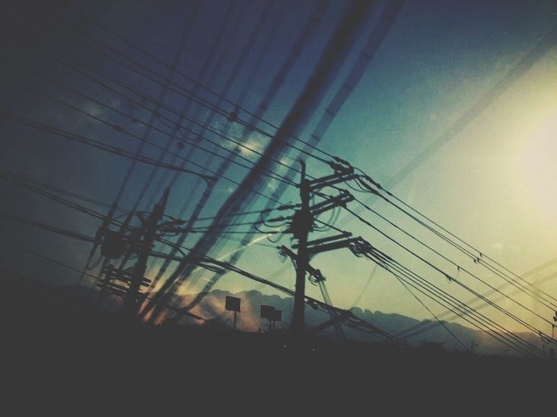 silhouette, low angle view, electricity pylon, power line, built structure, electricity, sunset, sky, architecture, fuel and power generation, power supply, building exterior, connection, cable, technology, sun, dusk, sunlight, outdoors, no people