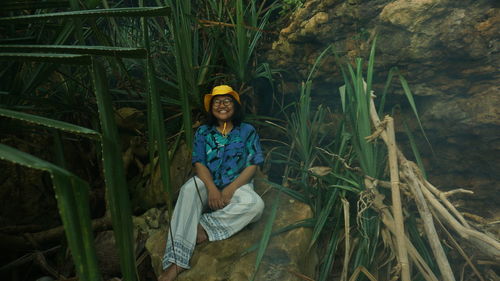 Portrait of smiling young woman sitting on plants