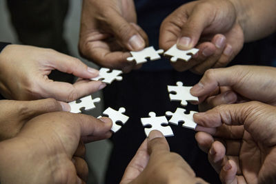 Cropped hands holding jigsaw pieces at home