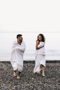 A couple in love spend the night at the sea, kissing and hugging on the beach covered with a blanket