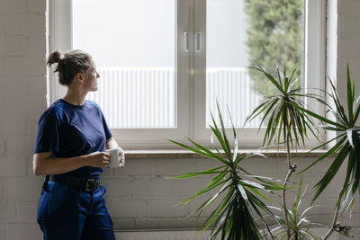 Young woman working in high tech enterprise, taking a break, drinking coffee