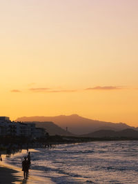 Silhouette person on sea against sky during sunset