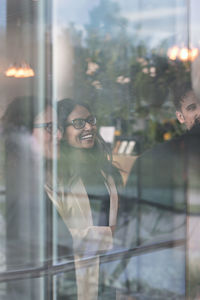 Cheerful business people talking in office seen through glass