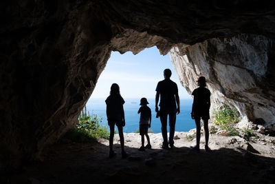 Silhouettes of tourists standing in the entrance of a cave