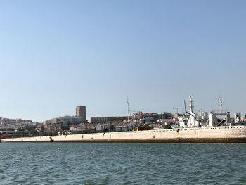 View of sea and cityscape against clear blue sky