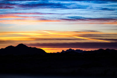 Scenic view of dramatic sky over silhouette landscape