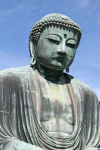 Low angle view of large buddha statue against blue sky