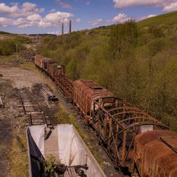 Abandoned train on landscape against sky