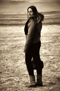 Full length portrait of smiling woman standing on field