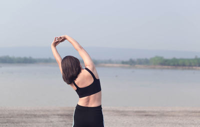 Woman standing at beach against sky