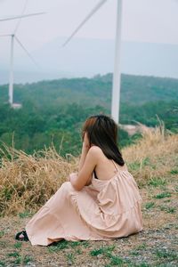 Rear view of woman sitting on field