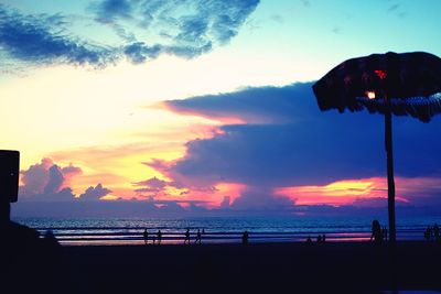 Silhouette people on beach against sky during sunset