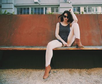 Full length of woman sitting against wall