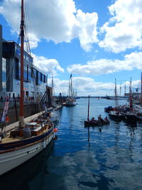 Boats moored at harbor against sky