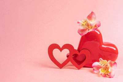 Close-up of heart shape on pink flower against red background