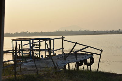 Gazebo by lake against clear sky during sunset