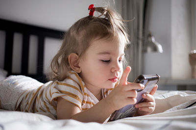 Boy using mobile phone while lying on bed at home