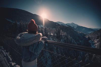 Rear view of people on mountain against sky during winter