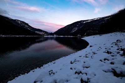 Scenic view of lake by snowcapped mountains against sky during winter