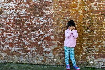 Portrait of girl standing against wall