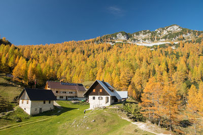 House amidst trees and houses against sky during autumn