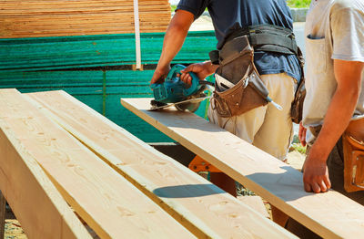 Midsection of carpenters working outdoors during sunny day