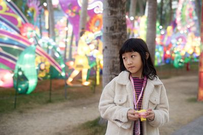 Cute girl standing in illuminated carnival