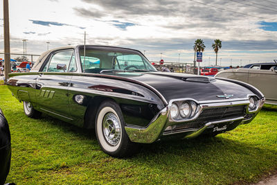 Vintage car on field against sky in city