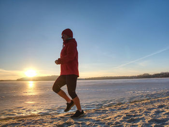 Woman or girl running in winter river park by evening. happy face of running woman within training 