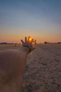 Man holding umbrella at beach during sunset