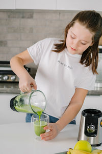 Portrait of young woman drinking water at home