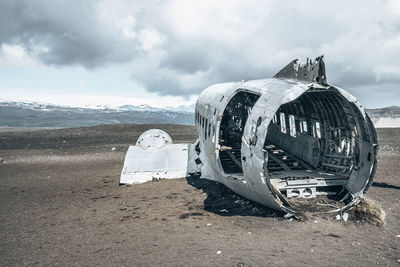 Broken military aircraft wreck at black sand beach in solheimasandur against sky