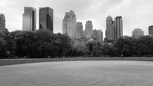 Trees and buildings in city against sky
