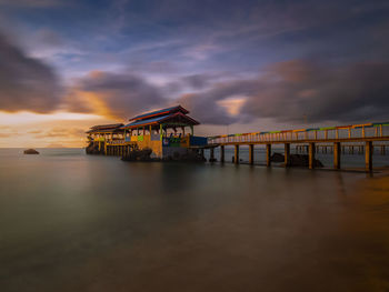 Pier over sea against sky at sunset