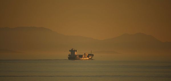 Silhouette boat in sea against sky during sunset