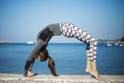 Young woman doing yoga against sea