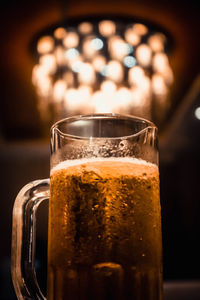 Close-up of beer in glass against illuminated lights