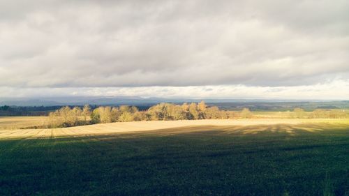 Scenic view of grassy field against cloudy sky