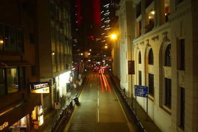 Illuminated street amidst buildings in city at night