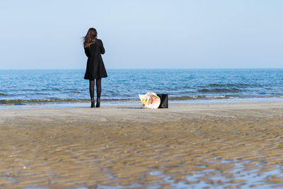 Rear view of woman standing at beach