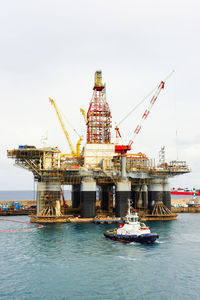 Cranes at oil rig against sky