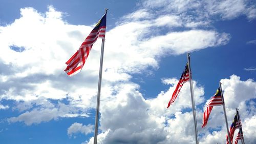 Low angle view of malaysian flags waving against sky