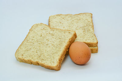 Close-up of bread and egg against white background