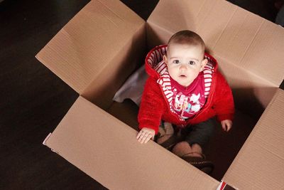 Portrait of cute baby girl in box at home