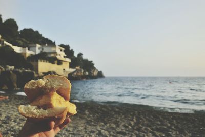 Close-up of hand holding ice cream against sea