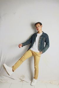 Portrait of young man standing against wall